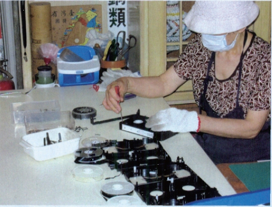 台北市中山八德环保教育站志愿工将一个录像带拆解，然后把各种不同部件分类回收再利用。