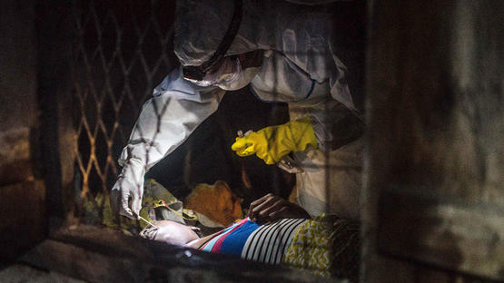 塞拉利昂，世卫组织的何塞·罗维拉（Jose Rovira）医生从一位疑似埃博拉死者身上棉签取血。 图片来源：Tommy Trenchard.jpg